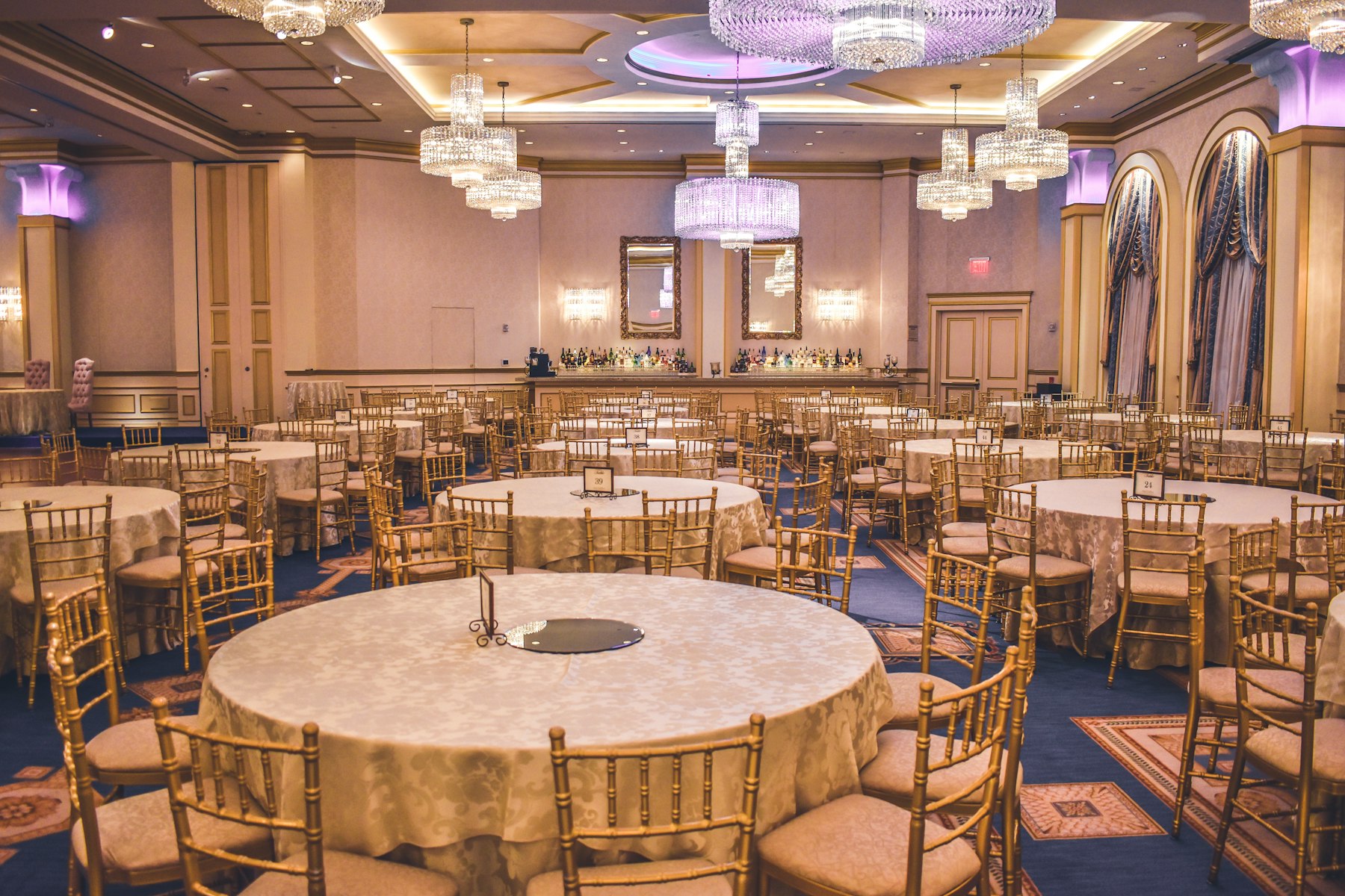 Salón de eventos con mesas redondas vestidas en tonos dorados para una boda