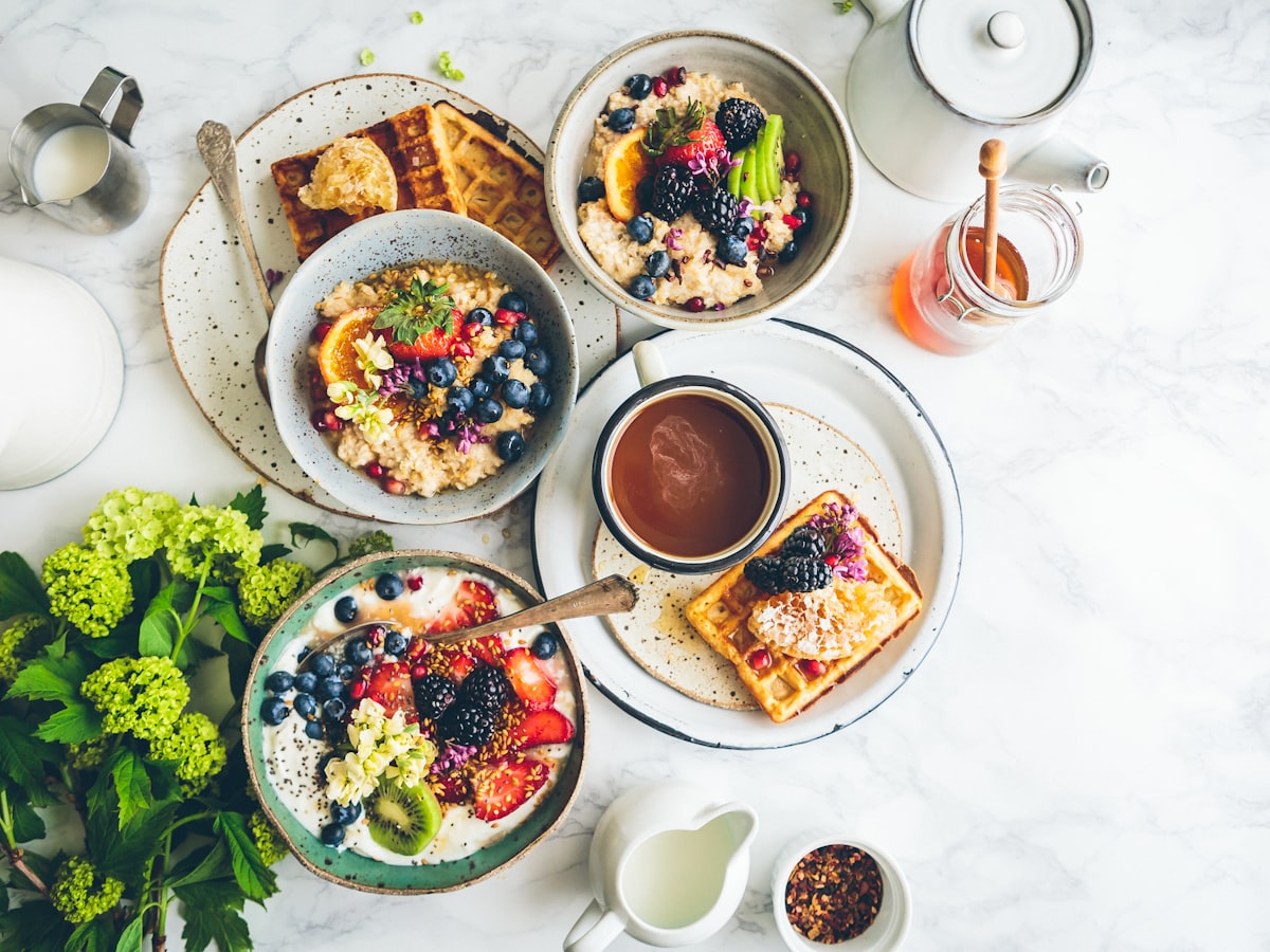Mesa de desayuno con fruta, waffles y café servidos con cuidado